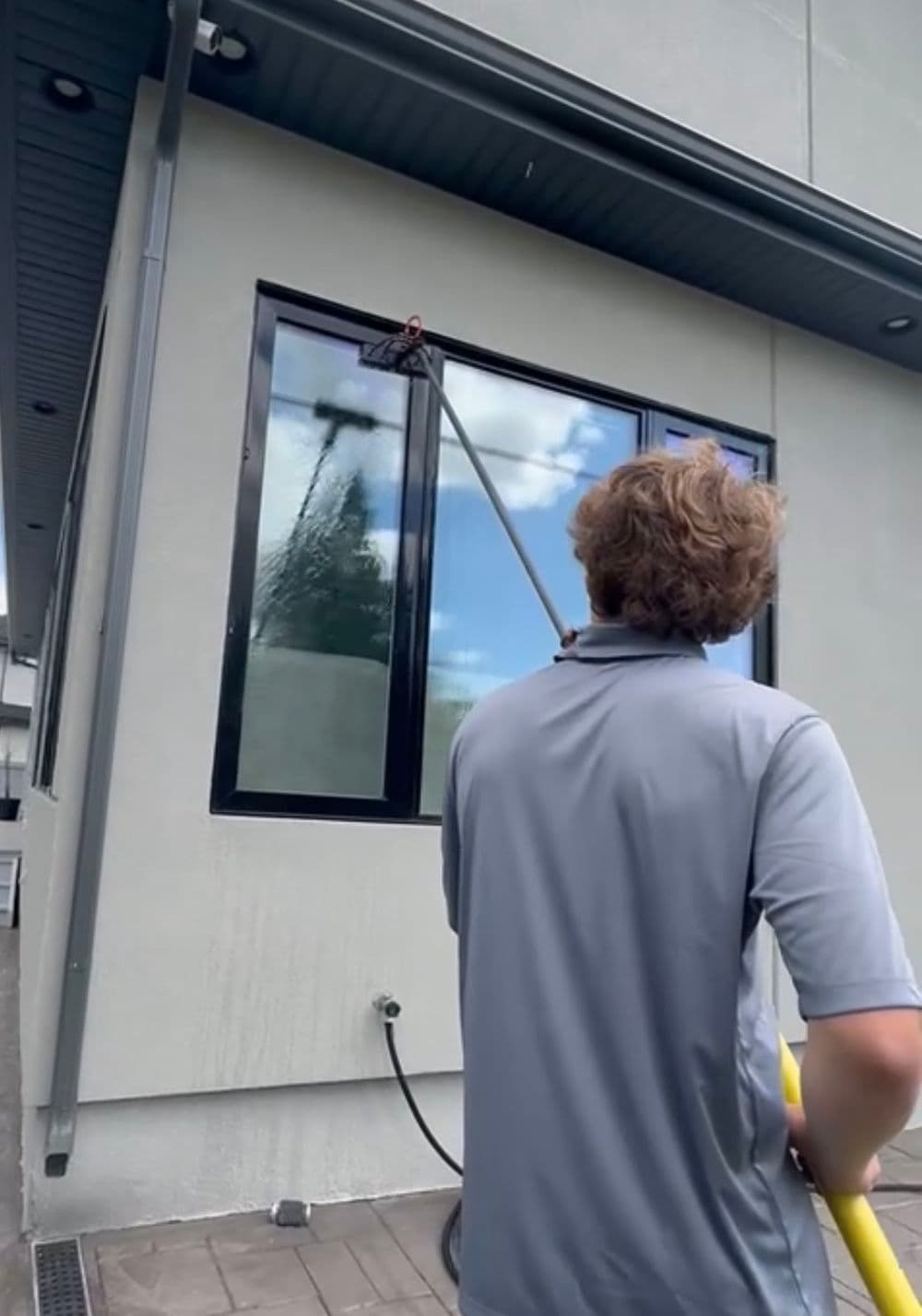 Man cleaning large window with a squeegee on a modern building exterior.