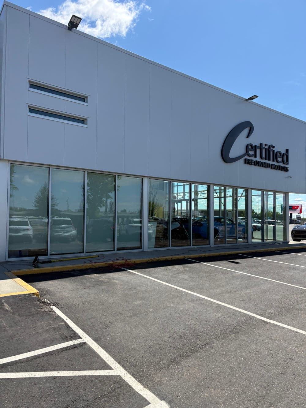 Certified pre-owned car dealership exterior with large glass windows and clear signage.